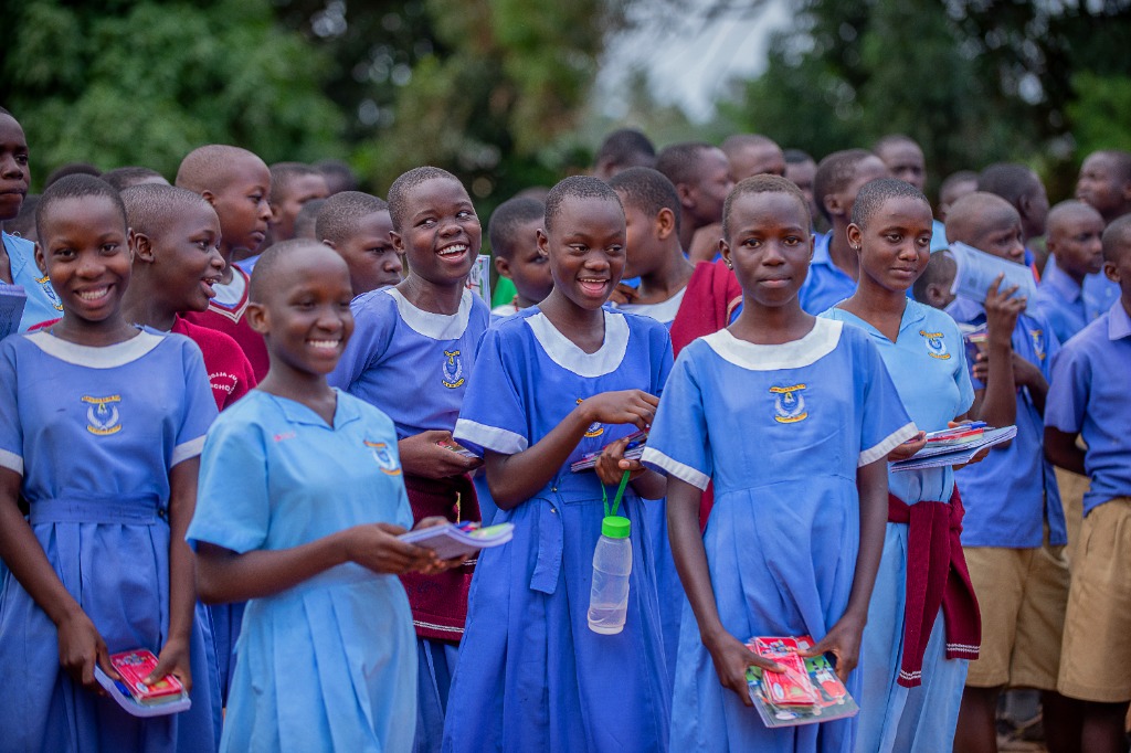 Smiling schoolgirls in blue uniforms holding learning materials and books