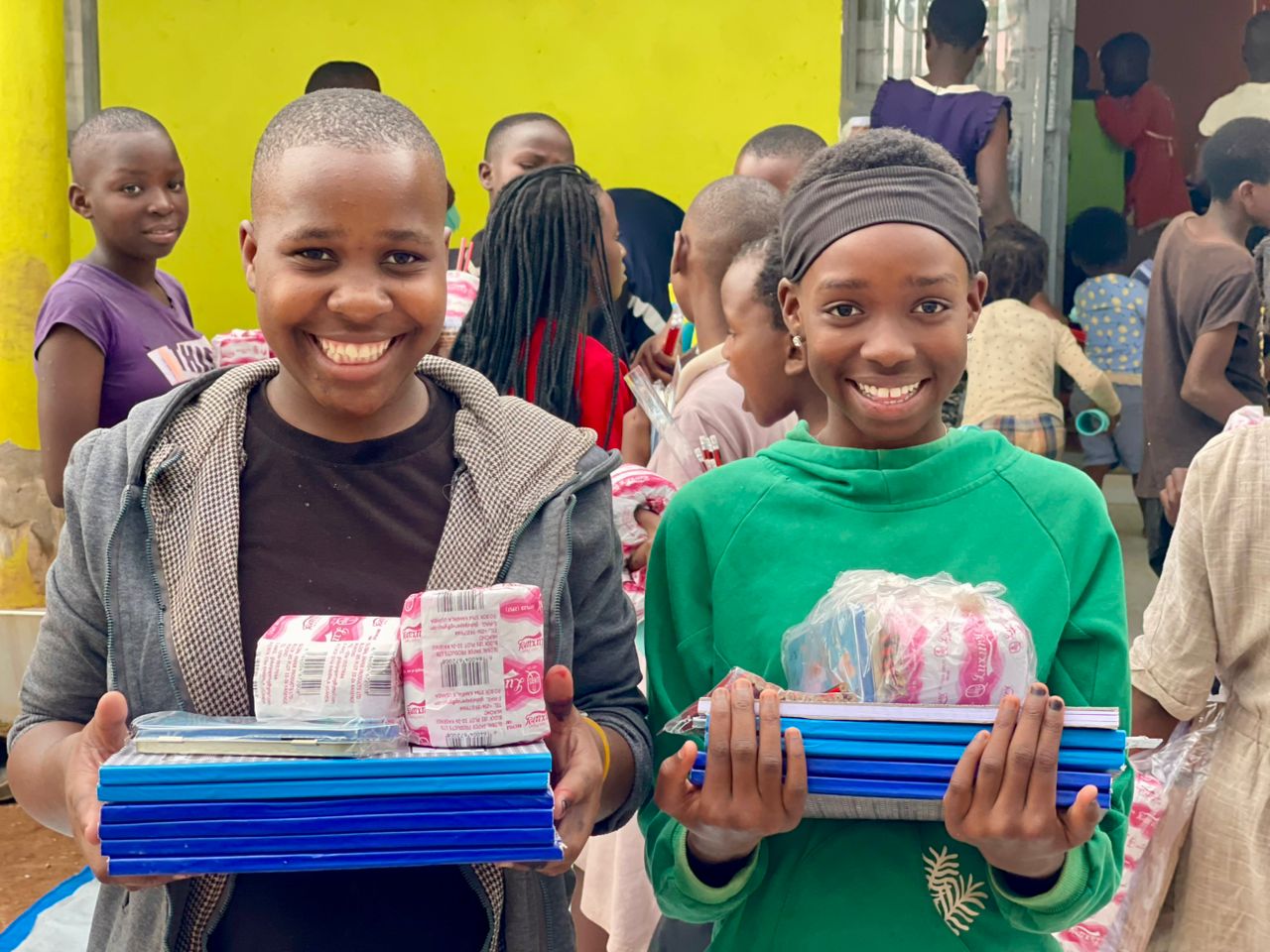 Two girls smiling while holding donated school materials