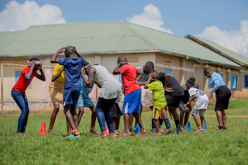 Children on the sports field engaging in head-and-cone agility drills